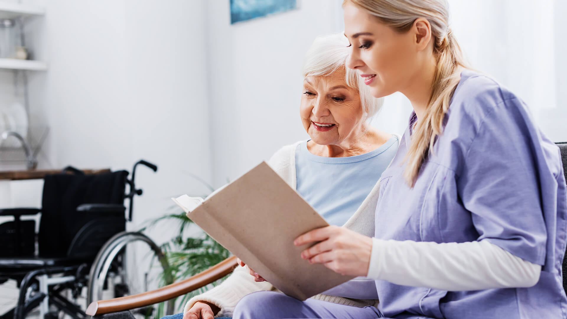 Pflegekraft von Seniorenbetreuung Ziegler liest Seniorin aus einem Buch vor